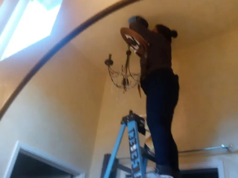 Electrician installing a chandelier in a Good Hope residence